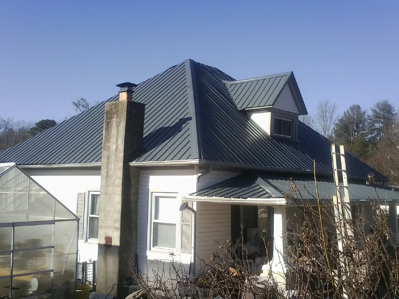 Dark blue standing seam metal roof on a white farmhouse with dormer — Slate & Tile Roof Repair by Roofing Brothers in Delphi Falls
