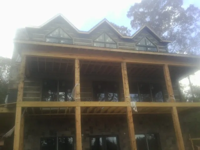 Dormers and porch framing on a large log home under construction — Roof Coating work by our crew in Delphi Falls