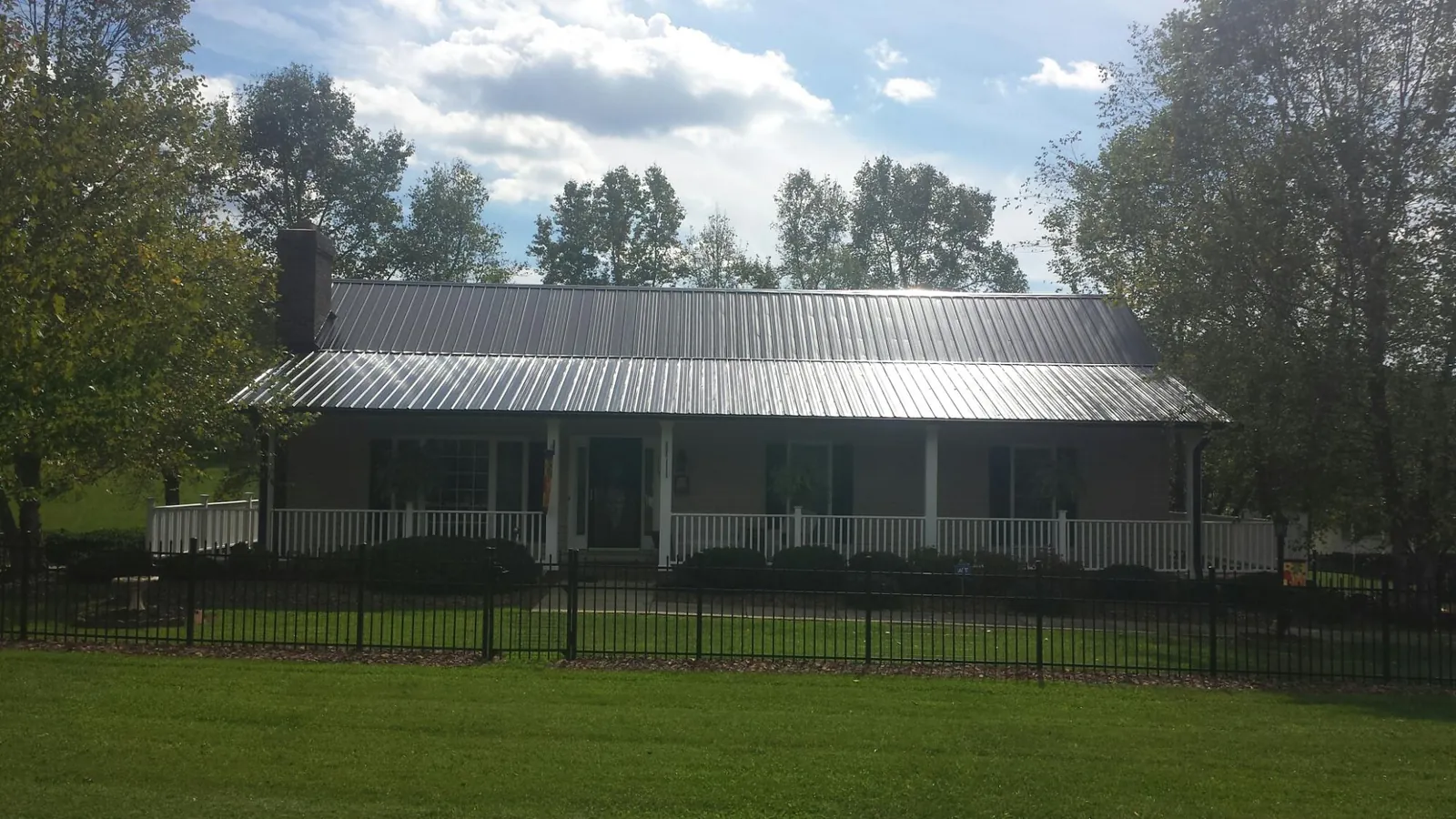 Gray metal roof on a brick ranch with a full width front porch — Gutter Guard Installation work by our crew in Delphi Falls
