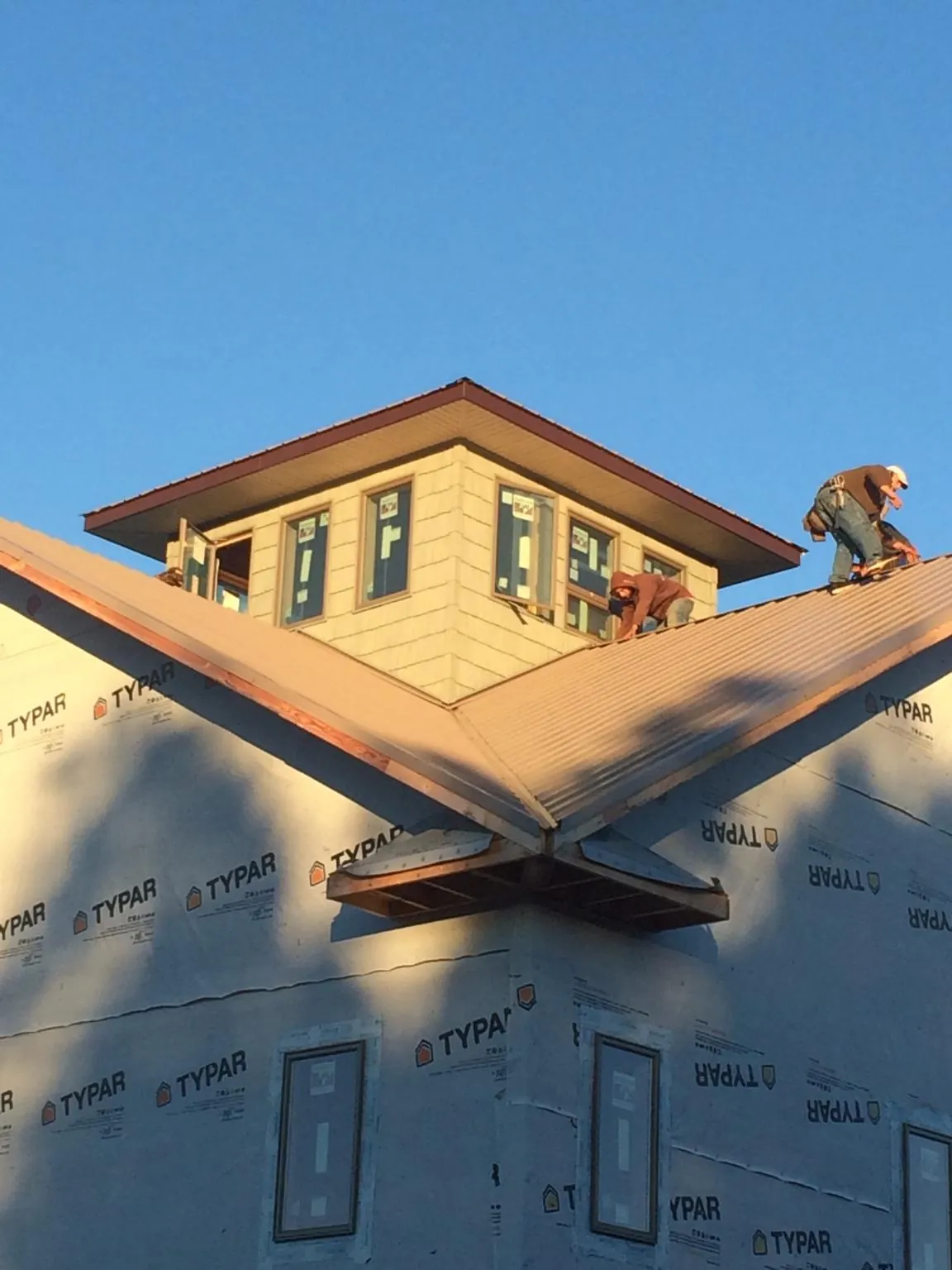 Roofers working around a rooftop cupola on a new metal roof at sunset — Roof Waterproofing in Delphi Falls by Roofing Brothers